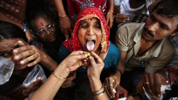 A woman opens her mouth to receive ‘fish medicine’.