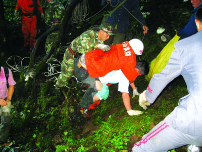 袁岚明(戴白帽者)从谷底被救援人员救出