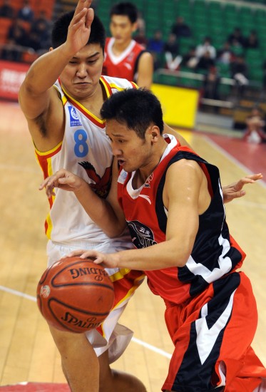1月4日,青岛双星队球员卢可明(左)在比赛中防守云南红河队球员赵阿南