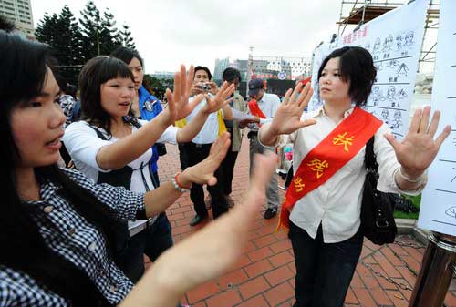 5月16日,一名聋哑人志愿者(右一)在福州市五一广场教市民学手语.