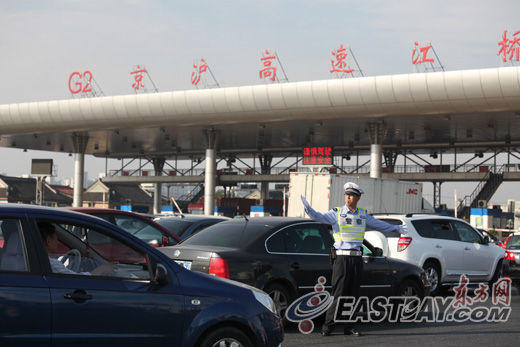 图为交警在g2京沪高速收费站前对车流进行疏导,提醒驾驶员快速通过.
