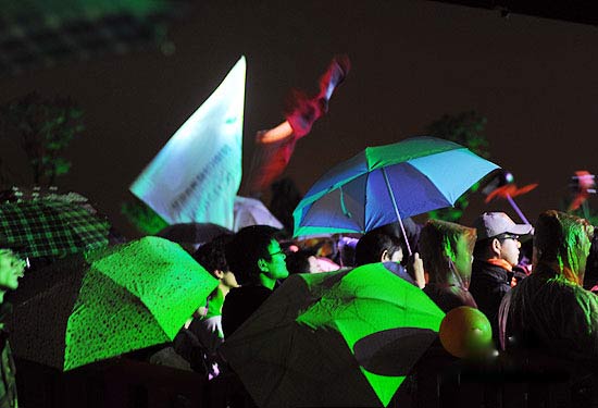 大批歌迷撑伞观看乐队歌手在雨中对歌迷竖起大拇指(唐朝乐队在雨中卖