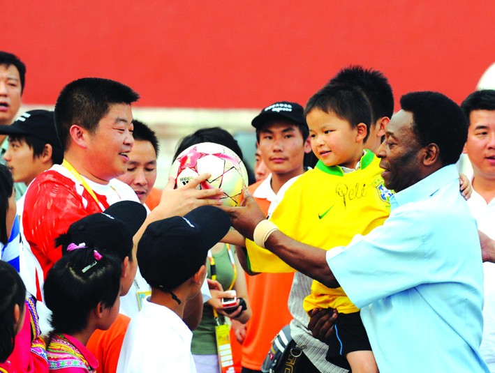 新华社发8月23日,贝利怀抱抗震救灾小英雄林浩向北京奥组委官员酝送