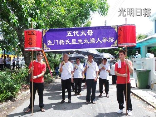 杨老太的家人在举殡队伍前举着横幅,送别尊敬的杨老太.