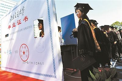 毕业生在毕业证模型前留影昨天,北京交通大学[微博]举行2014届本科生