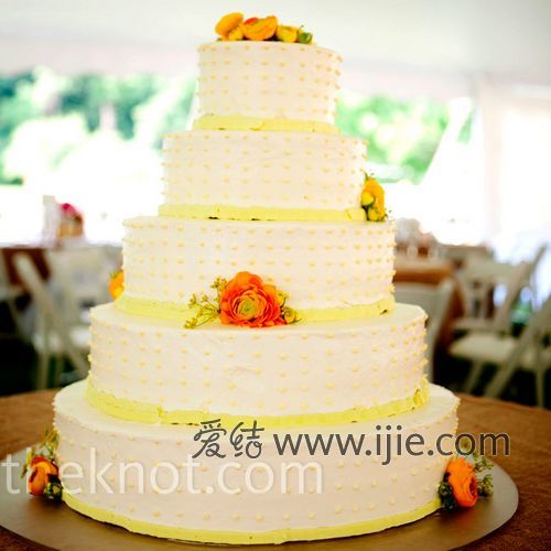 五层的婚礼蛋糕十分浪漫,上面装饰着黄色的波点和鲜花