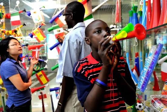 一名非洲男孩在义乌国际商贸城采购球迷用品时吹起三管彩色喇叭
